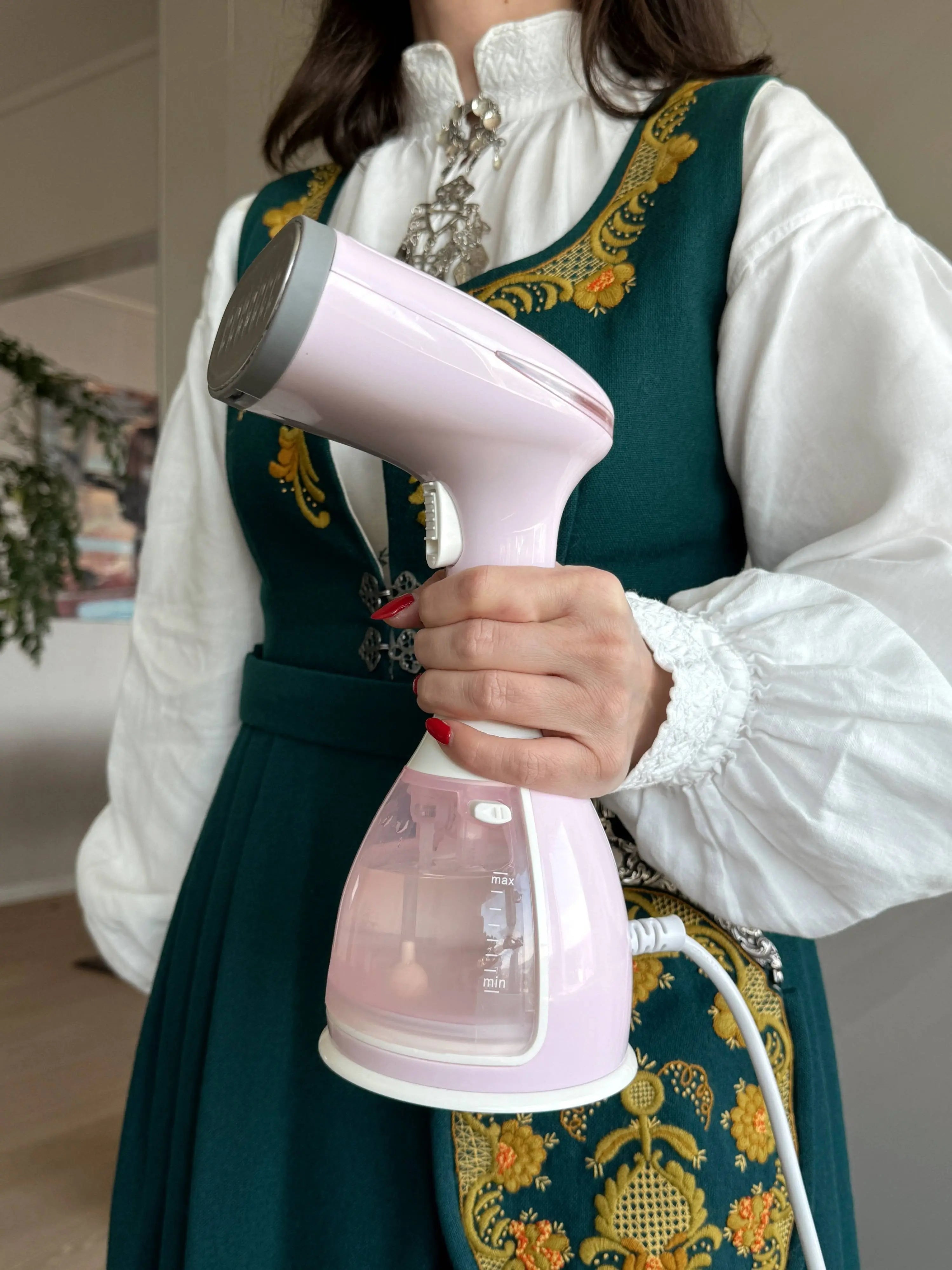 Rosa Silkify steamer holdt i hånden ved steaming av klær